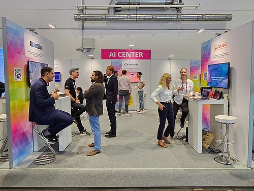 AI Center Messestand mit mehreren Personen, die in Gesprächen sind