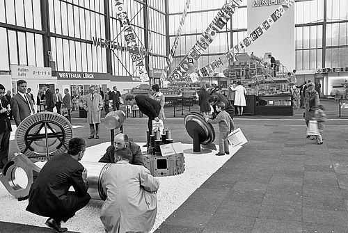 Ein historisches Bild einer Messe in Westfalia Lünen. Es sind mehrere große Schiffsteile zu sehen mit vielen Messebesuchern, Erwachsene sowie Kinder.