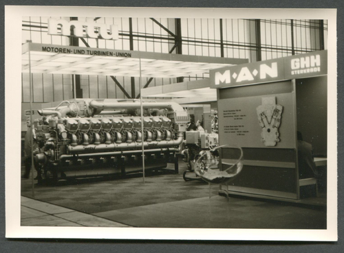 Historisches Bild eines Messestandes der Motoren- und Turbinen-Union, mit einer großen, ausgestellten Turbine.